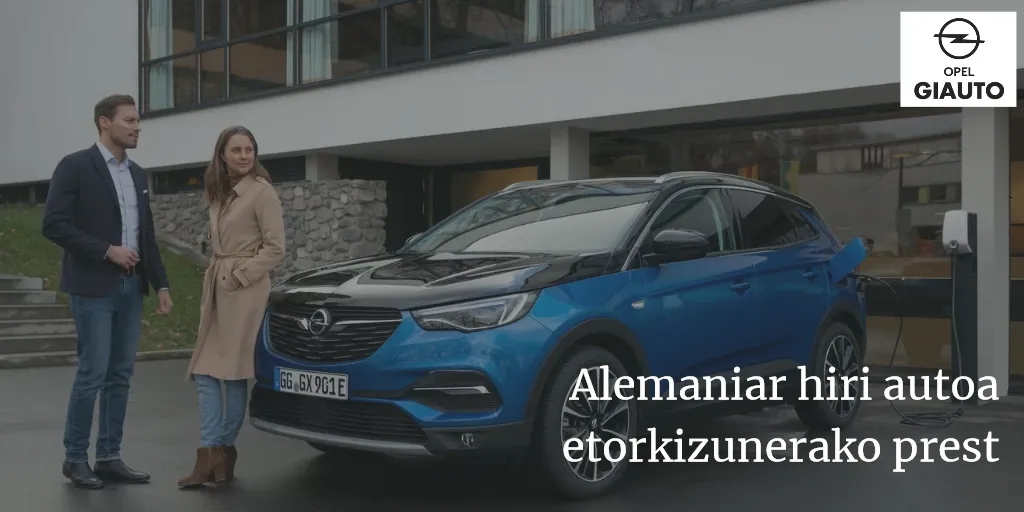 Anuncio de Opel Giauto con un todocamino azul enchufado a un punto de carga: «Alemaniar hiri autoa etorkizunerako prest»